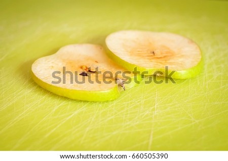 Two thin green apple slices on a cutting board turned brown due to the oxidation process close up stock image.