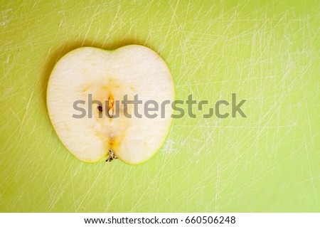 A thin slice of green apple on a cutting board. Apple is a source of numerous vitamins: vitamin a, vitamin b1, vitamin b2, folic acid. It is one of the world's healthiest foods.