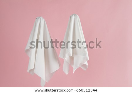 Couple of white sheet ghost isolated on a pink background. Minimal pop still life photography