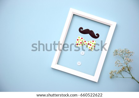 Photo frame, paper mustache, tie on blue pastel background with copy space. Greetings and presents. Happy Father's Day.