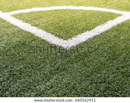 A corner line of the soccer (football) field with sunlight, in picture including a green turf and white line for demarcate inside and outside.
