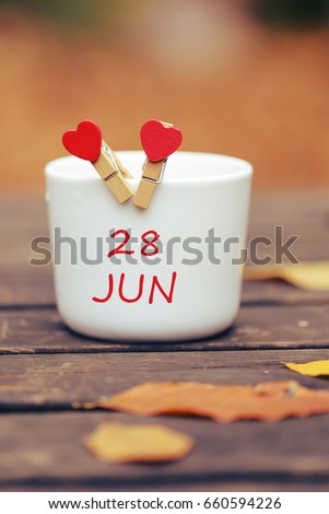 June 28. Day 28 of month, color calendar on morning coffee cup at nature background. Summer concept. Empty space for text 