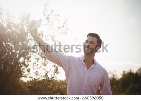 Low angle view of smiling young man taking selfie on day