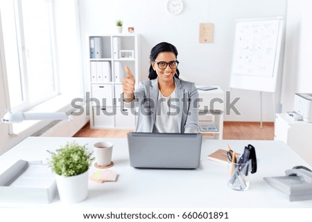 business, people and success concept - happy smiling businesswoman with laptop computer showing thumbs up at office