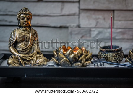 Mini, desk zen garden with lit candle and small Buddha in it.