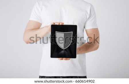 people, internet security and cyber protection concept - close up of man with virtual antivirus program shield icon on tablet pc computer screen over gray background