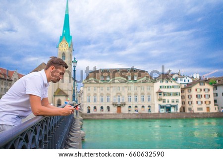 Young man taking selfie background famous Fraumunster Church and river Limmat.