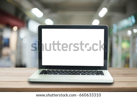 Laptop computer is blank screen on wood desk with blur office background.