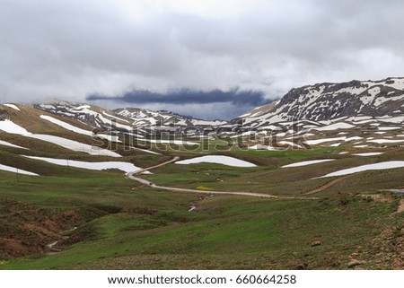 Horizontal shot of landscape with moutnains covered by melting snow
