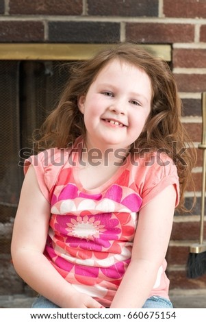 Portrait of a young smiling girl in front of a fireplace dressed for valentine's day