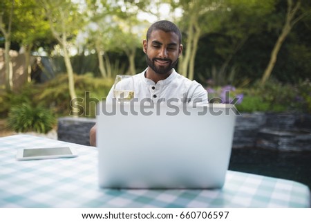 Smiling man holding wineglass while sitting at porch