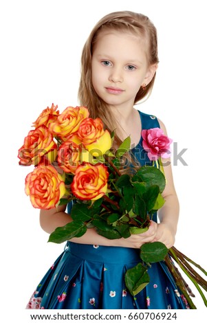 A beautiful little girl with long, light, curly hair, in a blue long skirt. She sits on a pink couch beside a large bouquet of tea roses.Isolated on white background.