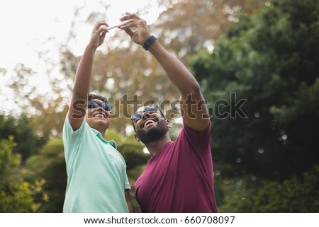 Low angle view of cheerful father taking selfie with son at park