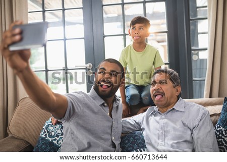Happy multi-generation family making face while taking selfie together at home