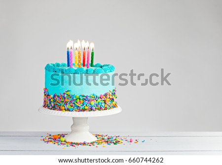 Blue Birthday with lit candles over light grey. Royalty-Free Stock Photo #660744262