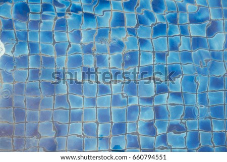 Top view wavy swimming pool with small textured blue ceramic tiles.