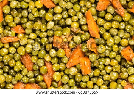 Prepared cooked green peas with carrot and wooden spoon.