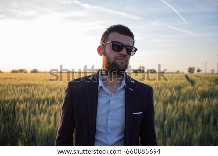 portrait of young handsome man in suit, summer field background 