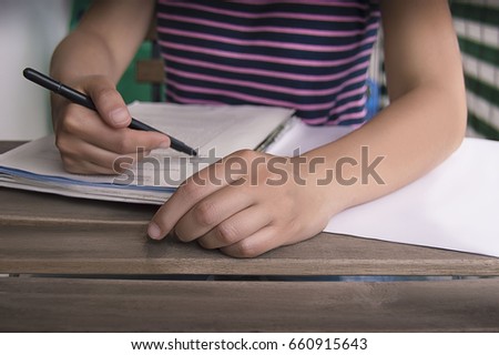 Person writing a document with hand in foreground on blurry background