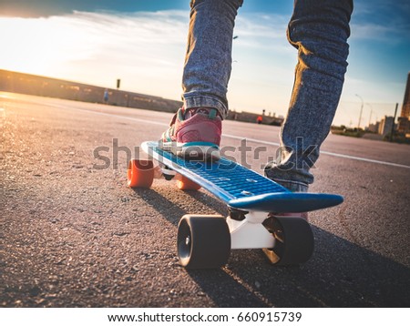closeup of the feet on the skateboard on the pavement and the evening sun