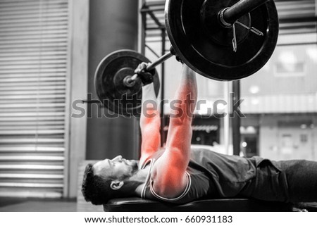 Side view of male athlete exercising with barbell at gym