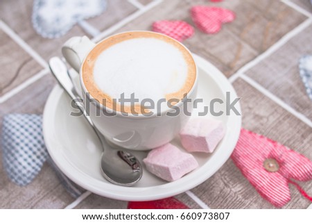 Cup of sweet morning energy drink is standing on tablecloth with a pattern in the form of hearts. romantic morning time
