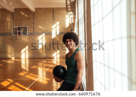 Portrait of a smiling basketball player holding a ball during practice in school.