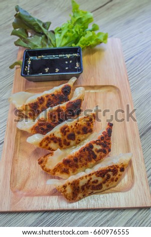 Dumplings (wonton) grill on wood dish serve with soy sauce is Asian cuisine, arrange for this vertical picture.