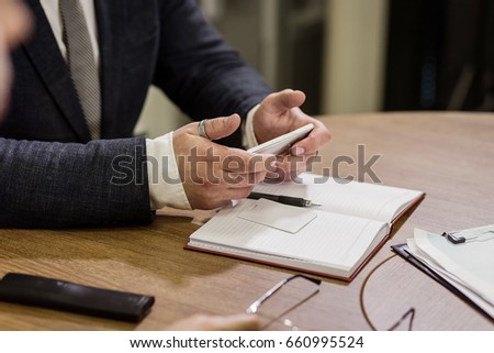 Businessman holding a cell phone and writing sms message in office