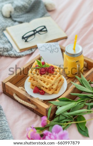 Wafers with orange juice and strawberries in a wooden tray. Concept of a romantic breakfast in bed
