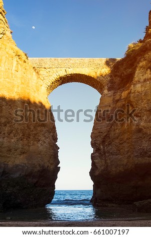 Arch on Praia da Batata in Lagos, Portugal with waves rolling in at low tide