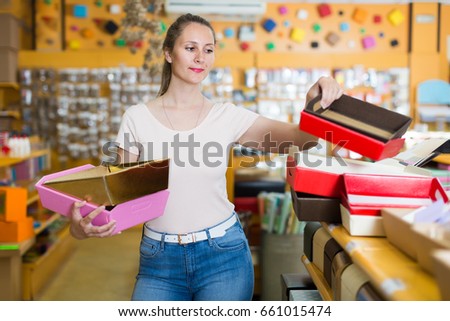 Smiling girl with gift boxes in her hands chooses accessories for gift in store