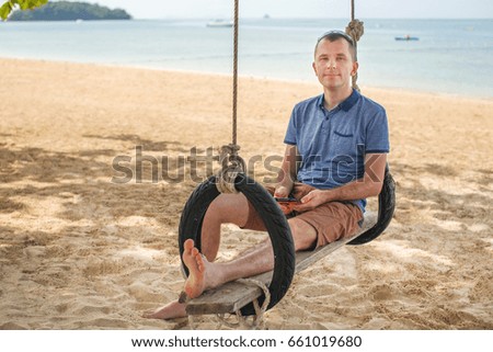 The man is sitting on a swing and relax. Lifestyle concept. Thailand, Krabi. February 2017.