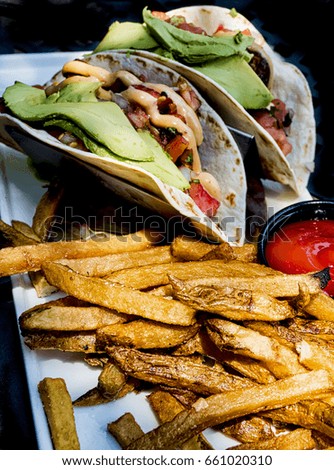 Two fish tacos with golden french fries.