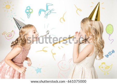 Portrait of cute girls in cone hats with party blowers