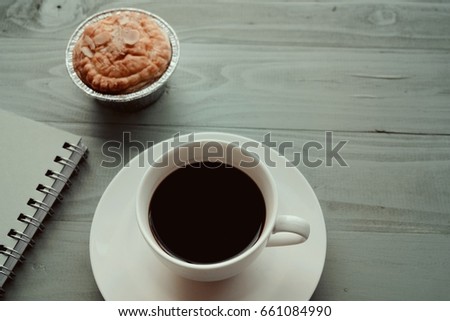 Black coffee , muffin and diarybook on wooden table. Picture  that select focus and copy space that  have flare light