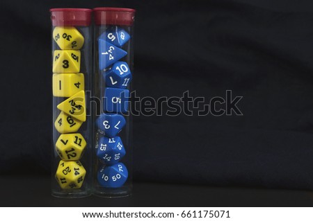 Dices for board games, rpg or tabletop games in storage tubes on black background