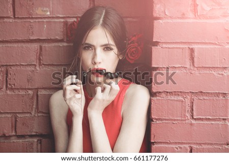 spanish woman with fashionable makeup and rose flower in hair, girl in red dress and black beads accessory on brick wall background, beauty and fashion