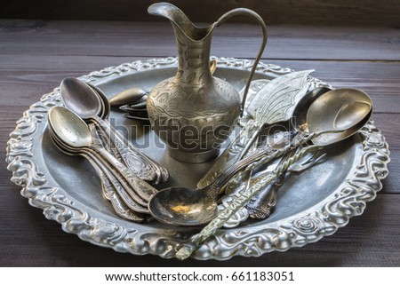 Old vintage silver kitchen equipment utensil tableware silverware with ornament pattern and small eastern jug on a tray on dark table Royalty-Free Stock Photo #661183051