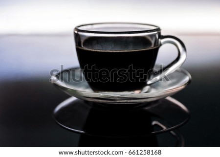 Fresh brewed Black coffee cup on reflective surface, with backlit background