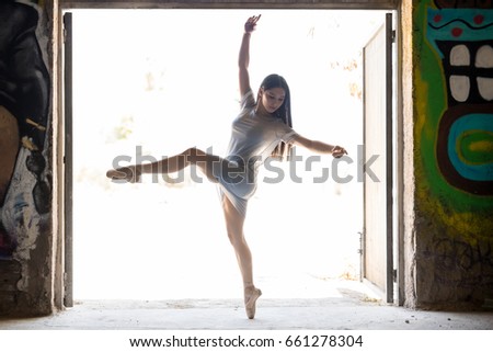Gorgeous young ballet dancer standing en pointe and performing a dance routine in an urban setting