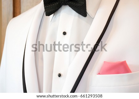 white tuxedo with black accent trim with bow tie and pink handkerchief in pocket Royalty-Free Stock Photo #661293508
