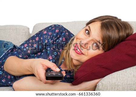 Picture of a pretty young woman lying on the couch, watching tv, with remote control in her hand