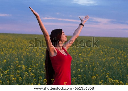 Girl in red dress enjoying nature and sunlight in the field