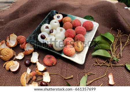 Close up plate of fruit on brown background, litchi or lychee fruits or Vai thieu. Red fruit peel with juicy pulp in white, sweet and delicious