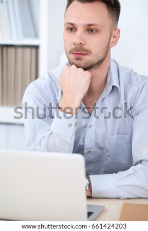 Portrait of businessman sitting at the desk in office workplace