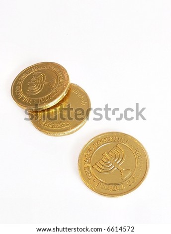 Three gelt coins on white background with slight shadow as a Hebrew holiday Hanukkah decoration. Vertical composition has one coin alone and the other two are loosely stacked. Coins have menorah image