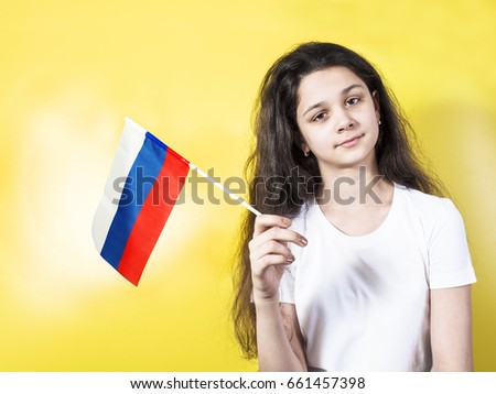 Smiling child, girl, holding a russian flag isolated on yellow background. 
