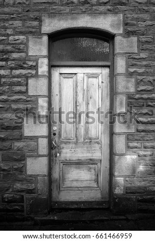 old faded wooden house door with stone wall