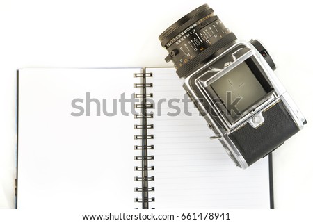 The photo shows a medium format camera with notebook on white background